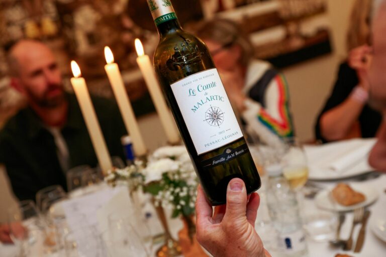 Main qui tient une Bouteille de vin chateau malartic